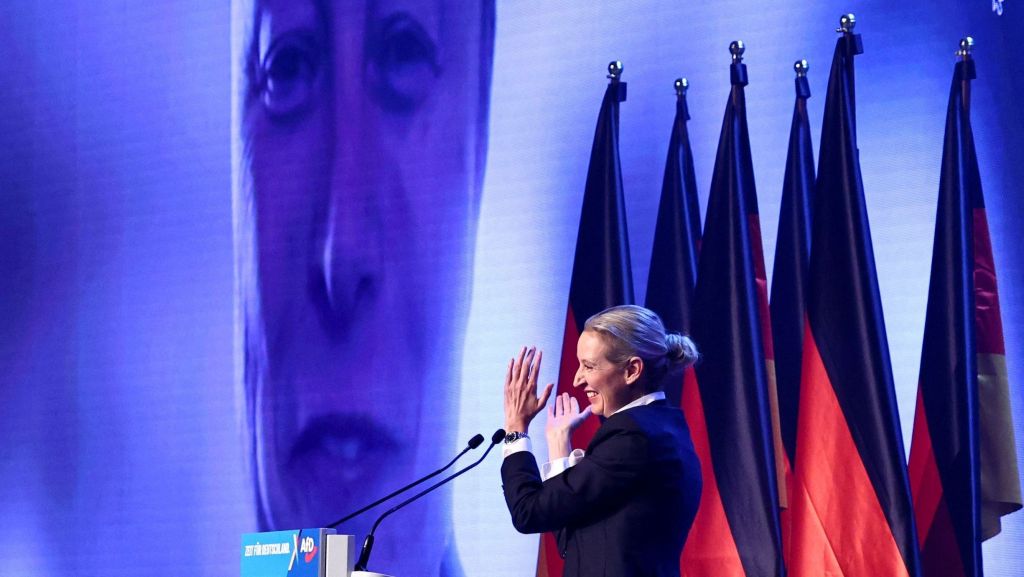 Alice Weidel, co-líder do AfD, partido de ultradireita da Alemanha, aplaude enquanto Elon Musk aparece na tela durante evento de campanha eleitoral em Halle, Alemanha